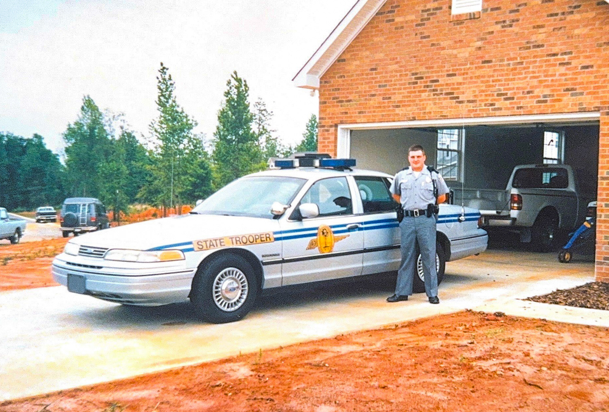Trooper Darnell posing with patrol car